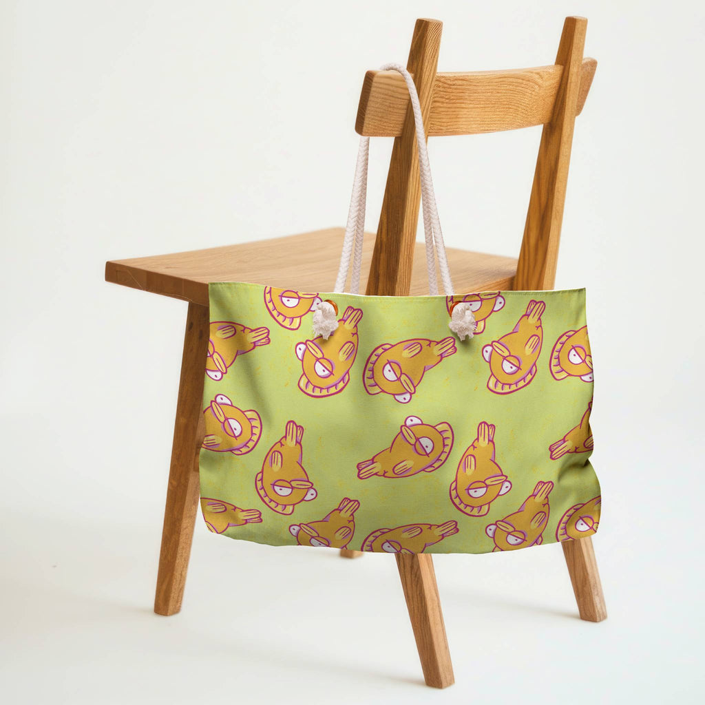 Green tote bag with funky fish pattern on a wooden chair against a white background