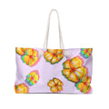 front view of a oversized beach bag featuring a chromatic hibiscus pattern on a light purple background