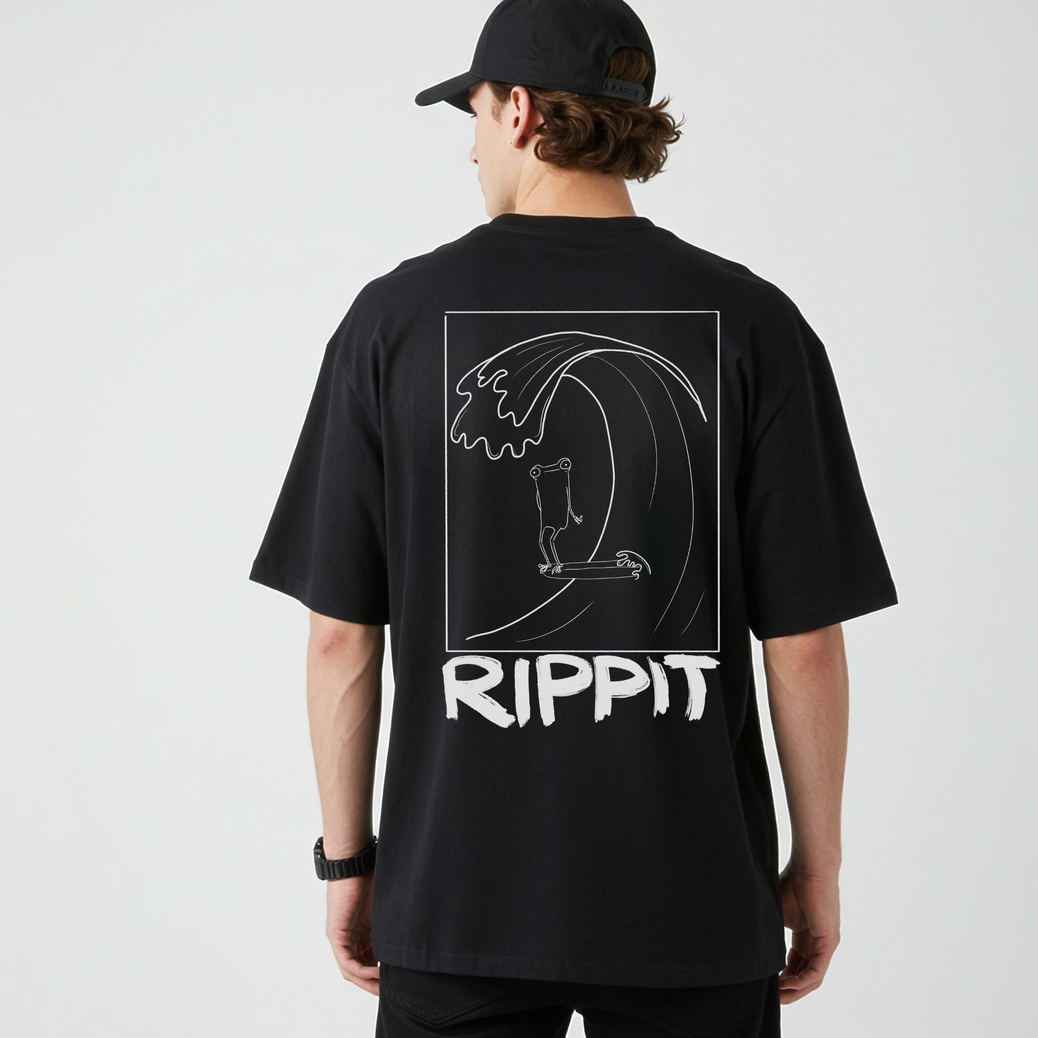 back view of a male model wearing a black surfjoy t-shirt with a design of a surfing frog and text that says 'rippit'