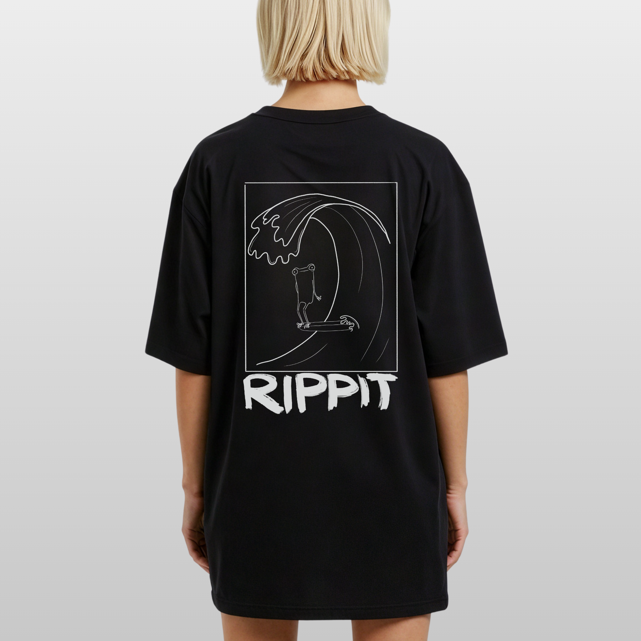 back view of a blonde woman wearing a black surfjoy t-shirt with a design of a surfing frog and text that says 'rippit'