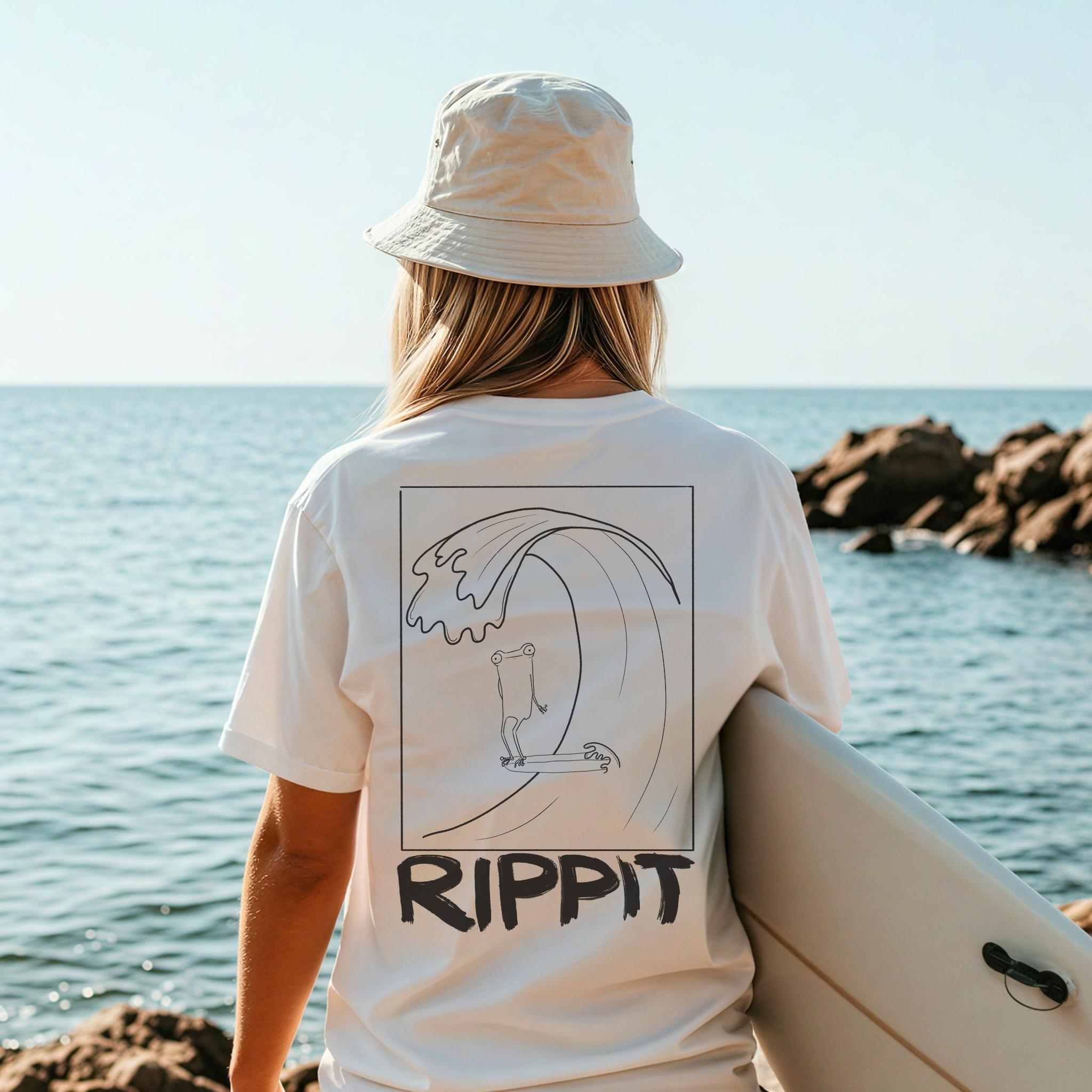 back view of a female surfing wearing a white surfjoy t-shirt with a design of a surfing frog and text that says 'rippit'