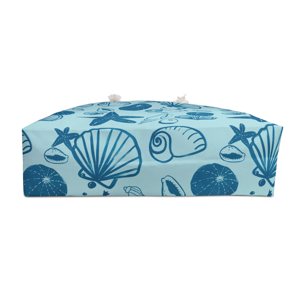 Bottom view of a blue beach bag with blue seashell pattern on a light blue background