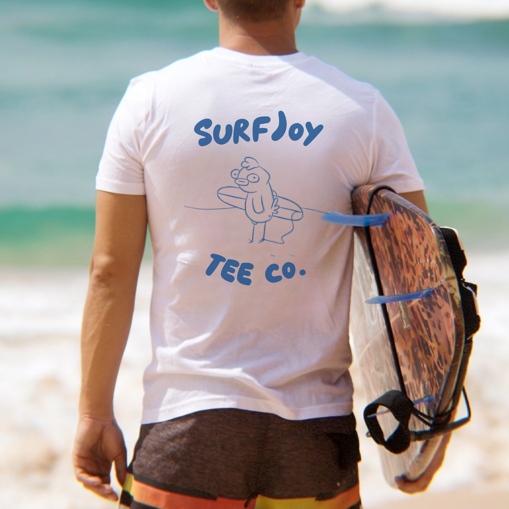 male surfer wearing a funny surf t-shirt with design of a chicken holding a surfboard on the beach