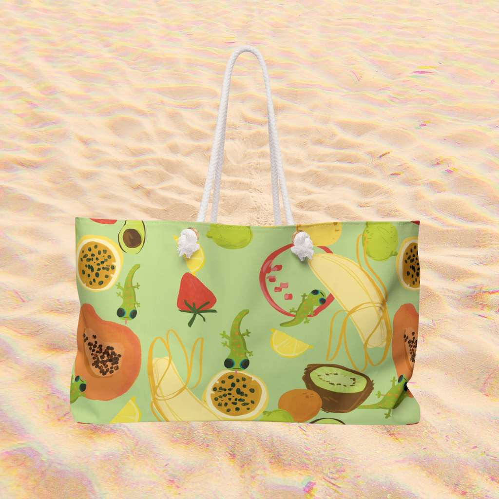 a cute lime green oversized beach bag with a tropical fruits and gecko pattern is shown on a sand background